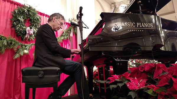 picture of Tom Grant donating his time and  playing piano on a stage for the homeless christmas dinner