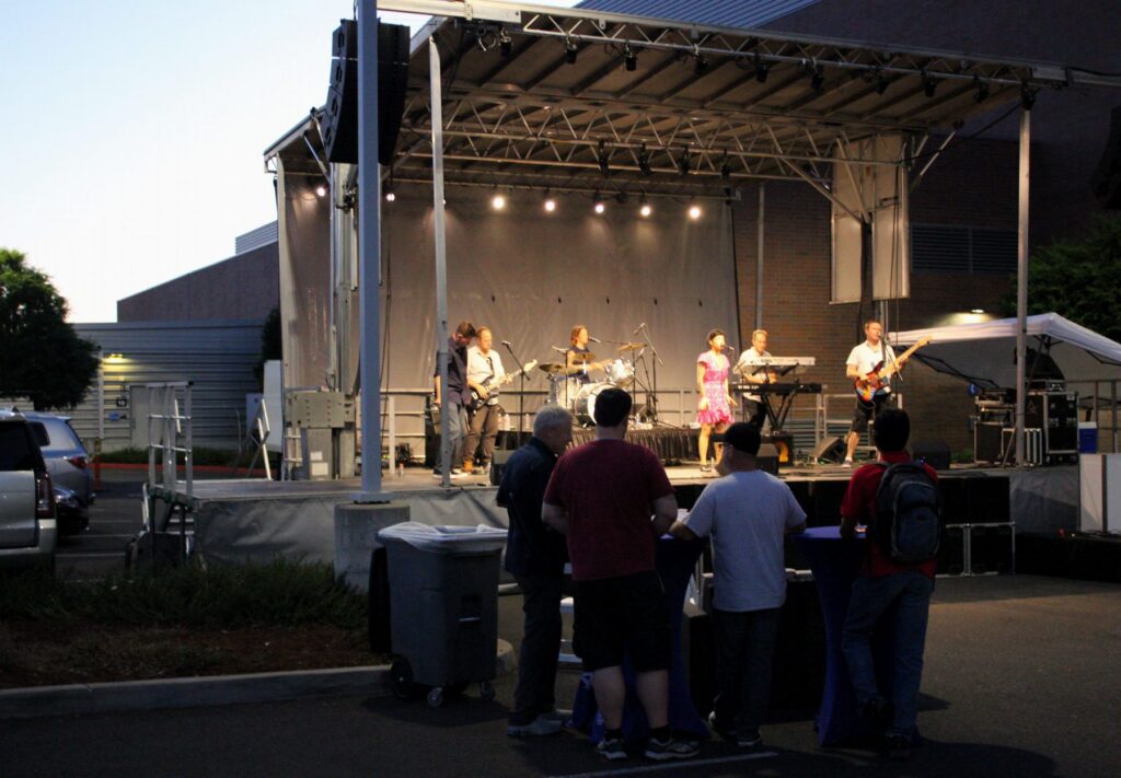 Outdoor corporate event stage at dusk with flown line arrays