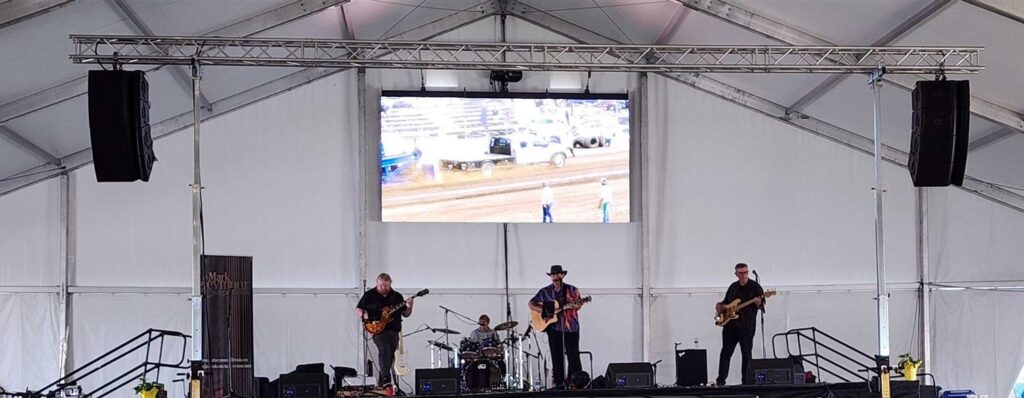 Festival tent stage with flown speakers and an LED video screen