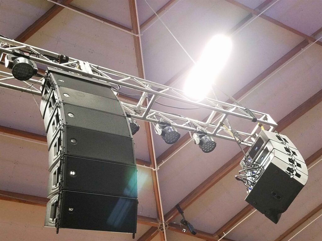 Line array speakers flown from truss inside an arena