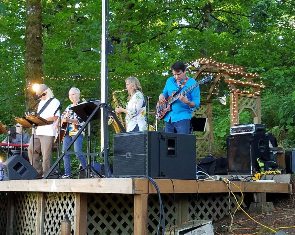 Live band performing on an outdoor stage in the trees