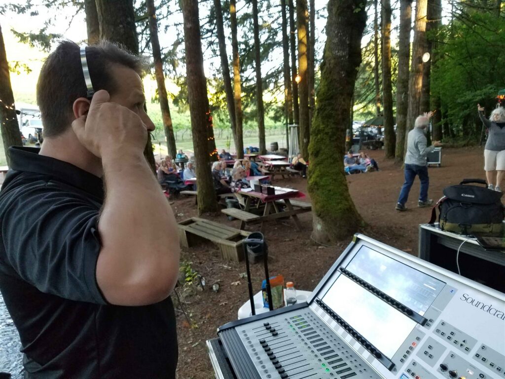Engineer monitoring a digital mixing console at an outdoor event